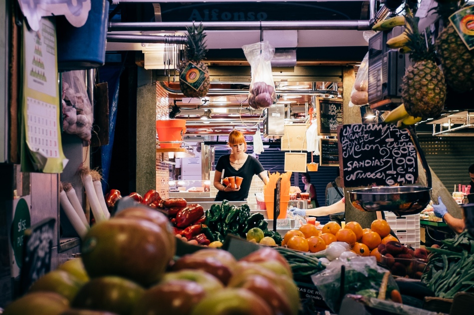 A woman arranges fruit juice as La Boqueria opens at 8 in the morning.
